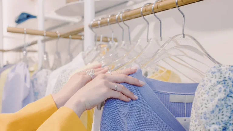 Closet Cosplay: 8 Character Builds From Wardrobe Basics 2 Closet cosplay planning: hands in a yellow sleeve pulling a periwinkle knit top from a rail of pastel shirts on clear hangers