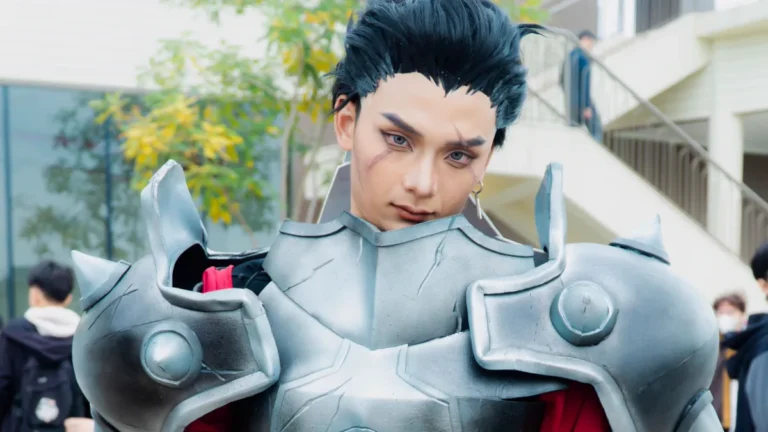Painted armor of the kind EVA foam cosplay builders make: silver pauldrons with round studs and a sculpted chest plate over a red outfit at a convention
