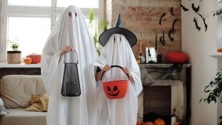 Family Halloween Costumes: 6 DIY Themes for 3 to 6 People 1 Family Halloween costumes made from white sheets: a parent and child dressed as ghosts, the child wearing a witch hat and holding a pumpkin bucket